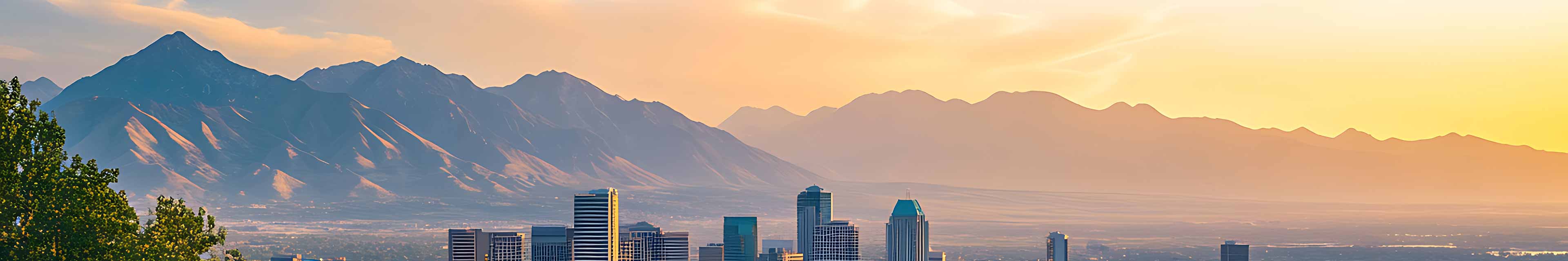 Photo panoramique de l’horizon de Salt Lake City avec les montagnes en arrière-plan, un ciel d’un bleu clair magnifique et une lumière à l’heure dorée.
