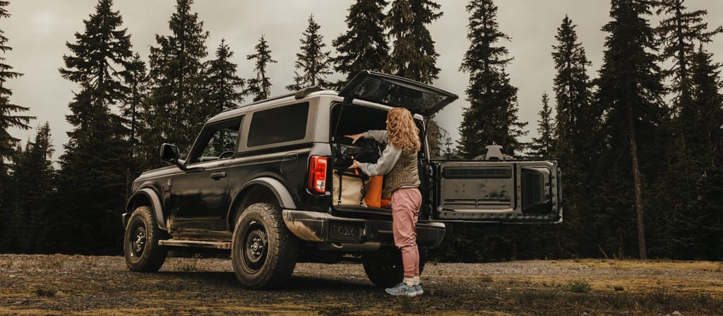 Une femme déchargeant de l’équipement de l’arrière d’un VUS Ford Bronco® 2025, montrant le hayon à ouverture latérale