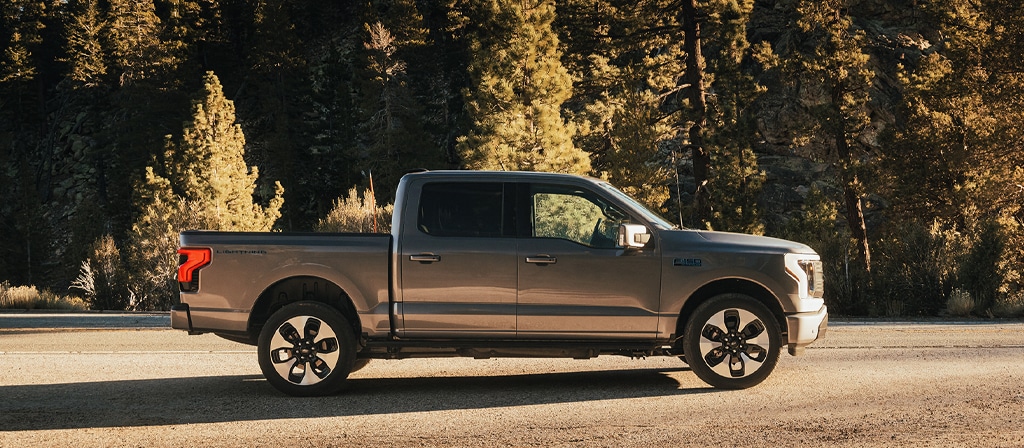 Une vue latérale du Ford F-150® Lightning® 2025 stationné au coucher du soleil dans un endroit pittoresque