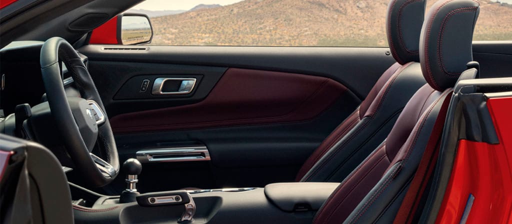 Ford Mustang® 2025 décapotable stationnée avec la portière du côté conducteur ouverte montrant l’intérieur rouge carmin en option