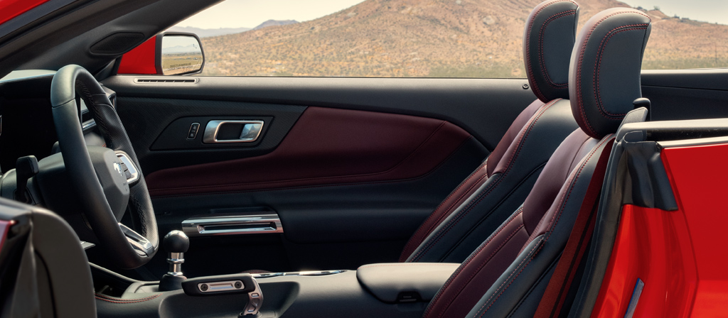 Ford Mustang® 2026 décapotable stationnée avec la portière du côté conducteur ouverte montrant l’intérieur rouge carmin en option