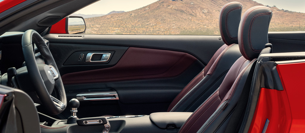 Ford Mustang® 2026 décapotable stationnée avec la portière du côté conducteur ouverte montrant l’intérieur rouge carmin en option