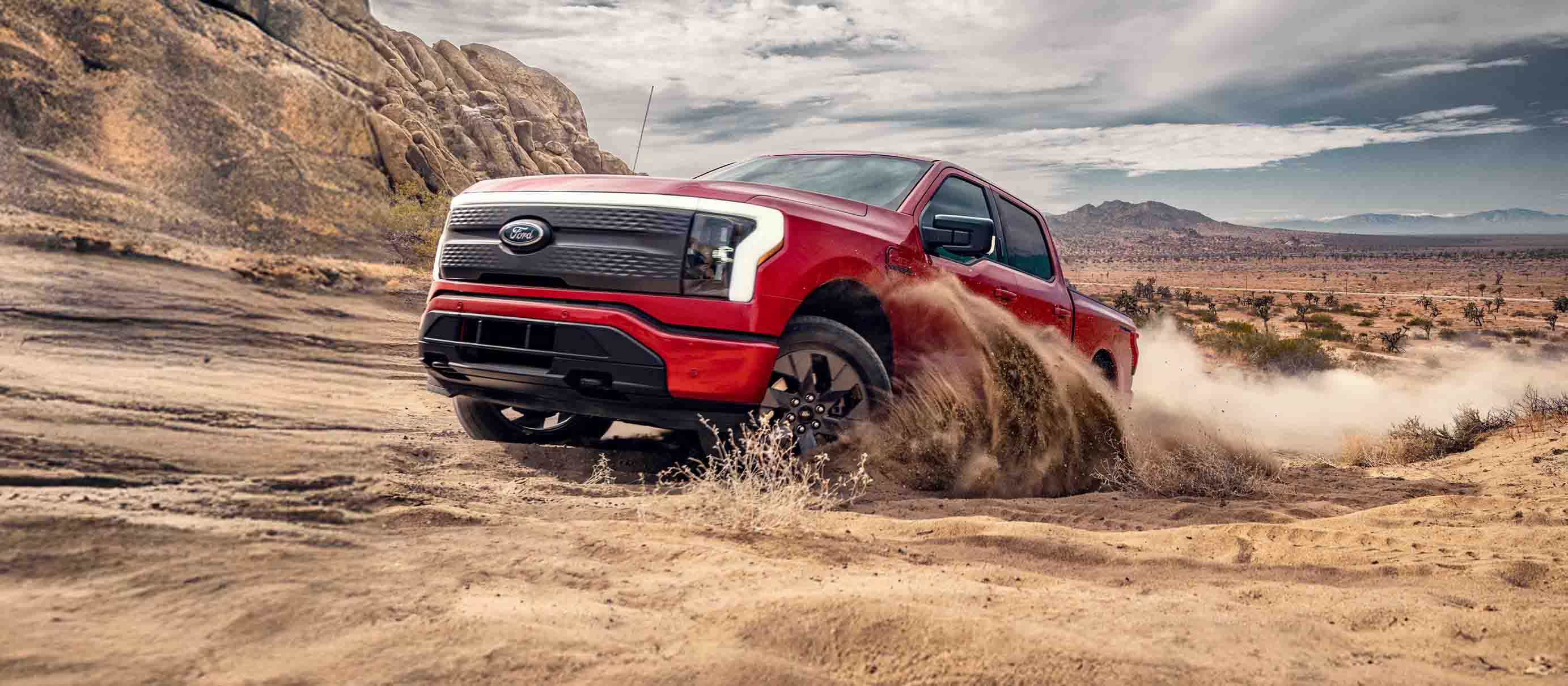 Un F-150 Lightning circulant sur un terrain accidenté et sablonneux.