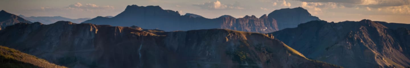 Une photo panoramique de coucher du soleil derrière une chaîne de montagnes