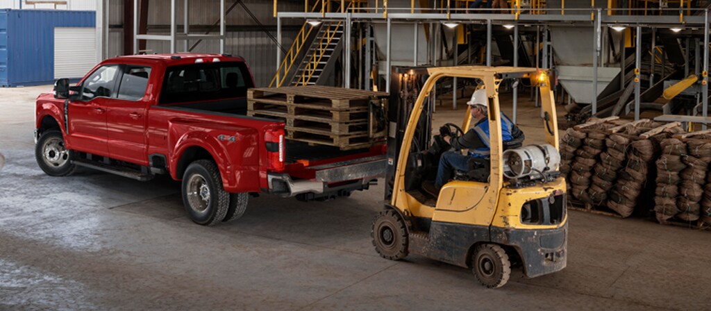 Modèle Ford Super Duty® F-350® Lariat® 2026 avec le hayon ouvert pendant qu’un chariot élévateur charge des palettes en bois dans la caisse du camion