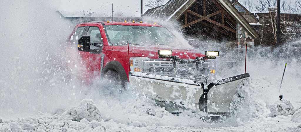Camion Ford Super Duty® F-450® XLT 2026 couleur rouge course circulant dans la neige lourde avec équipement de chasse-neige