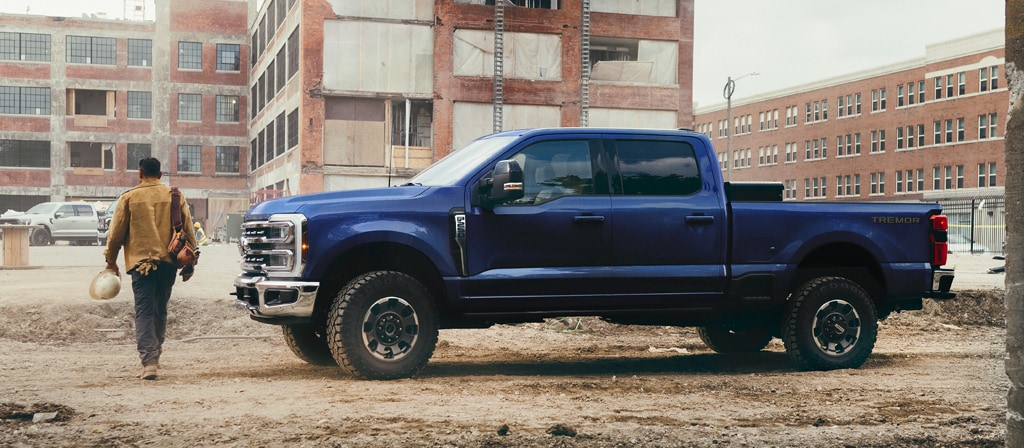 Une personne s’éloignant de son modèle Ford Super Duty® F-250® Lariat® 2026 en bleu argon sur un chantier de construction