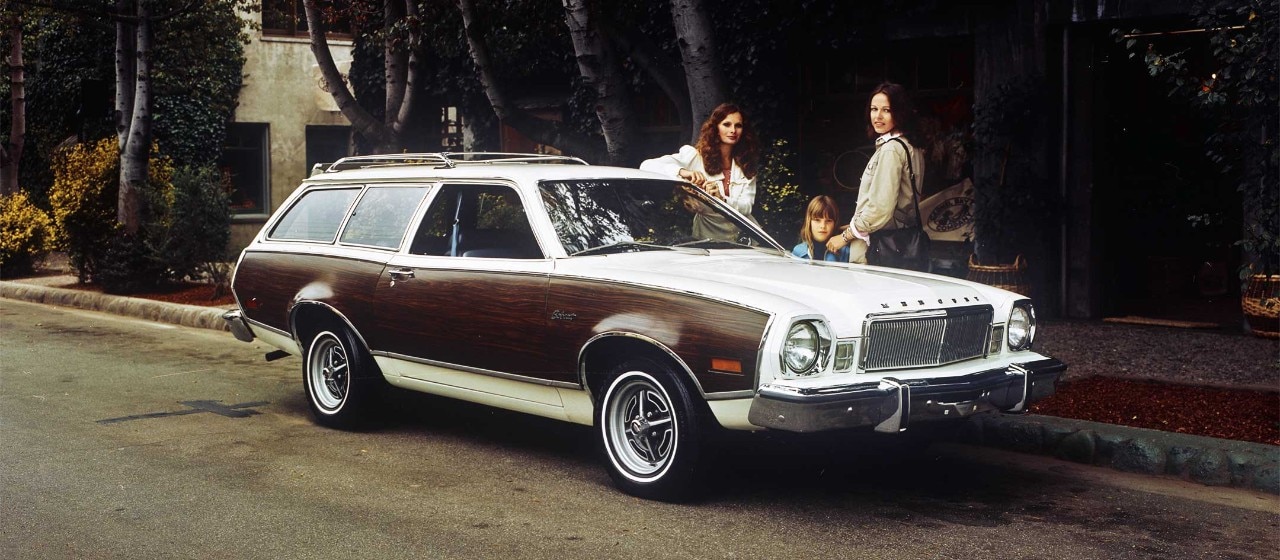 Deux femmes et un enfant debout près d'une familiale Mercury