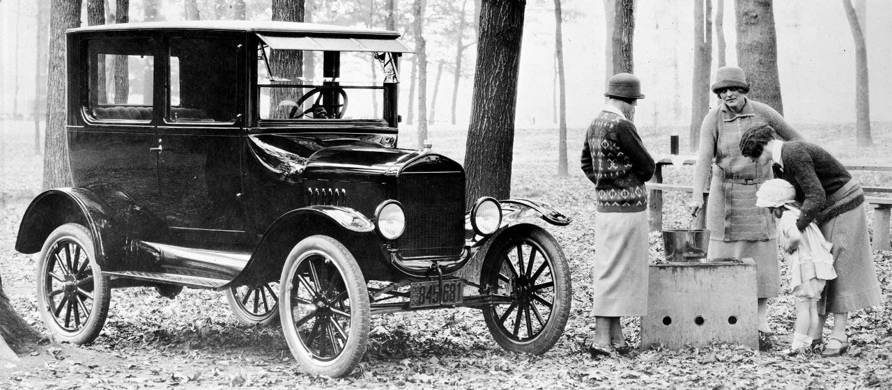 Un groupe de femmes et un enfant debout par une voiture de Ford d’avant-guerre
