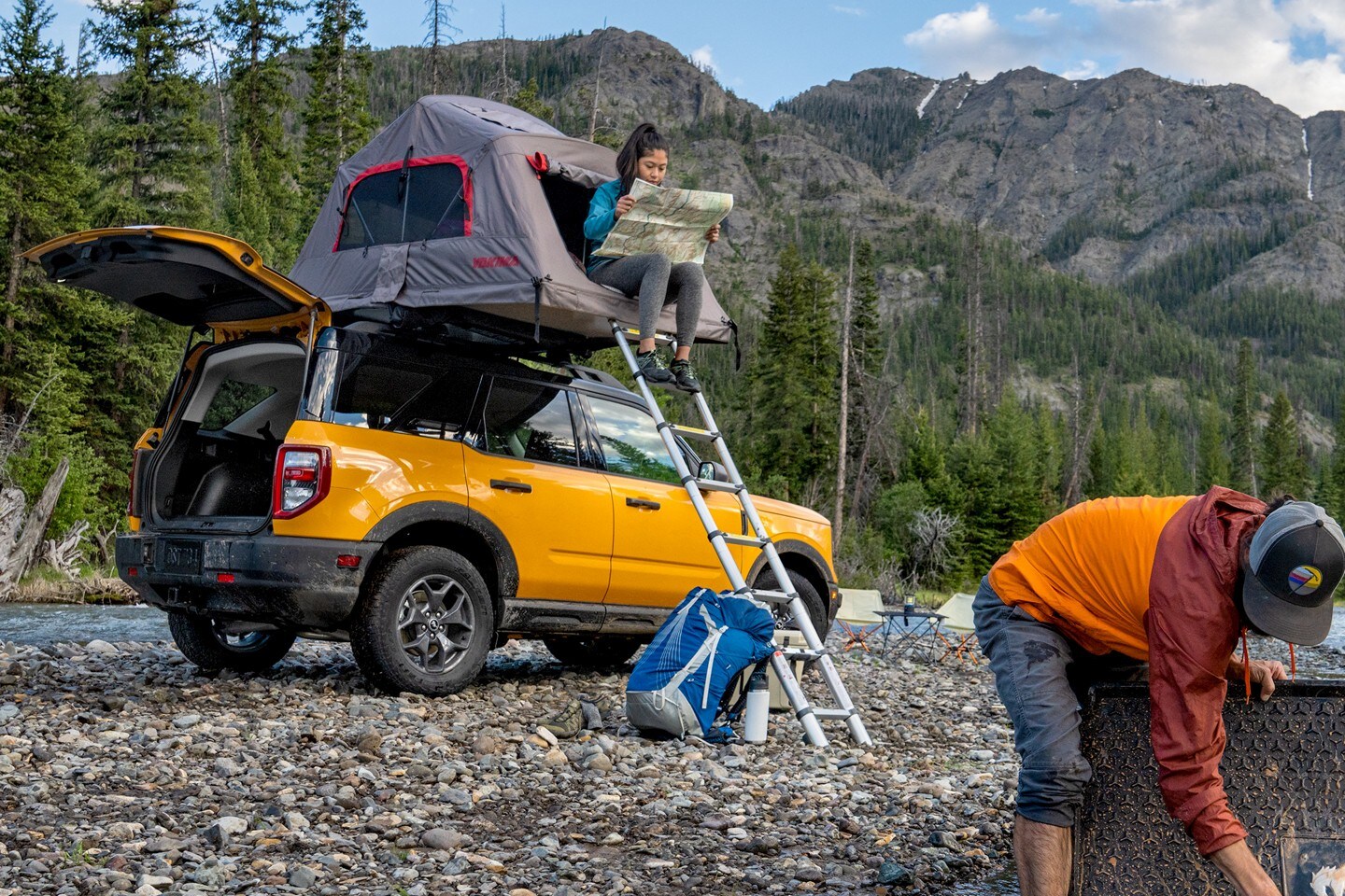 Un Bronco Sport jaune équipé d’un accessoire de tente stationné près d’une rivière