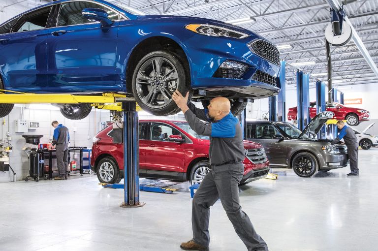 Mechanic inspecting a front tire in service bay