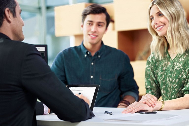 Un couple parle avec une personne chez un concessionnaire Ford