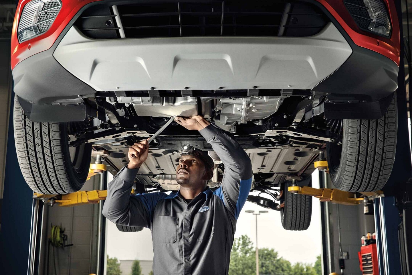 Un technicien travaille sur un véhicule électrique sur un élévateur.