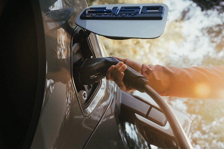 Une personne branche un câble de recharge sur un F 150 Lightning.