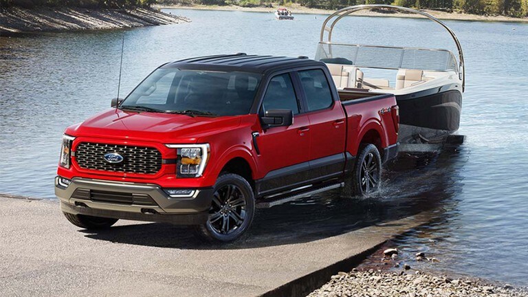 Un Ford F 150 2023 Édition Héritage rouge tire un bateau d'un lac