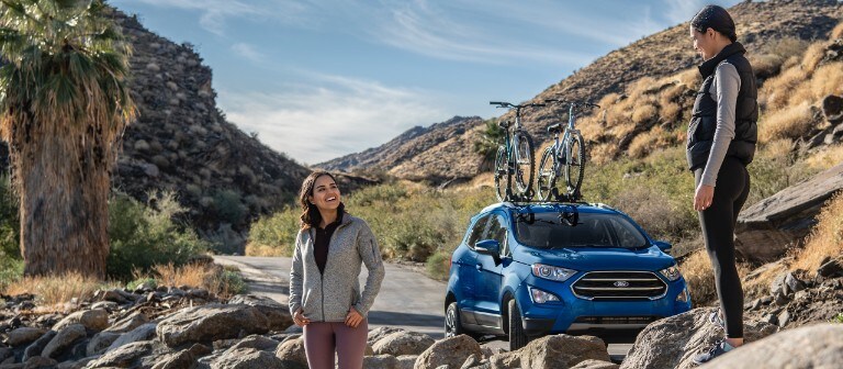 Un homme et une femme debout sur des rochers avec un Ford Escape 2021 garé sur la route à proximité