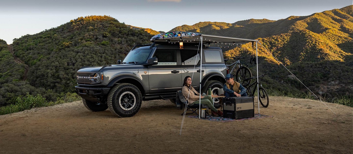 Un Ford Bronco Sport est stationné sur un sentier. Un couple s’en éloigne, marchant à côté de leurs vélos.