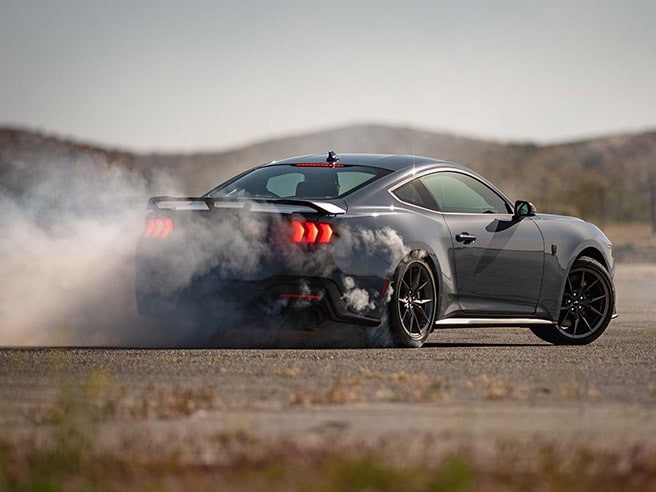 Les pneus fumants d’un coupé Mustang Dark Horse sur une chaussée déserte.