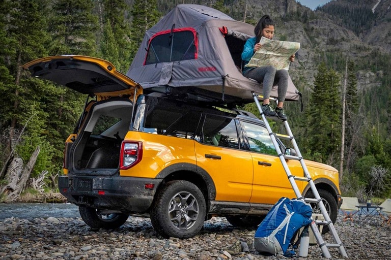 Une personne est assise dans une tente montée sur une Ford Bronco jaune
