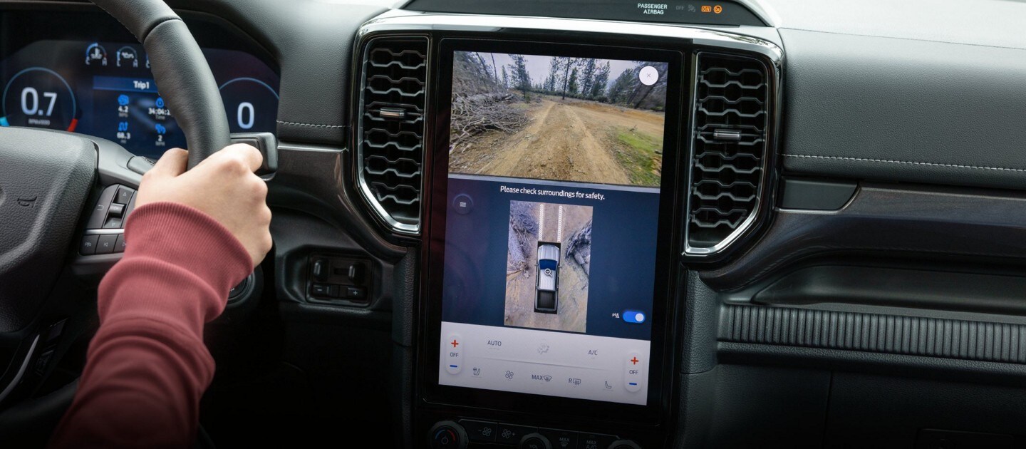 Un conducteur utilise la caméra de recul sur l'écran de la console multimédia d'un véhicule Ford pour l'aider à se garer.