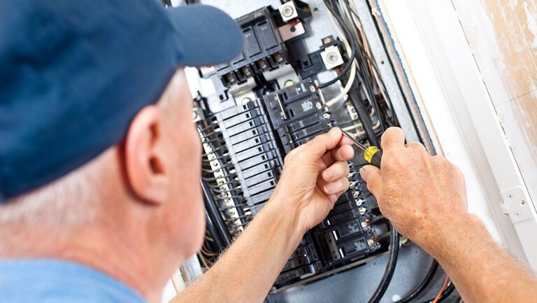 Un technicien câble un panneau de disjoncteurs