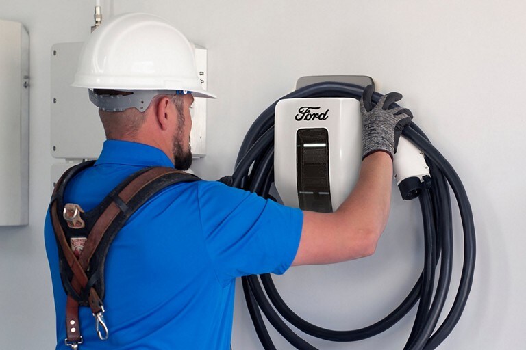 Un technicien installe une station de recharge Ford Pro sur un mur