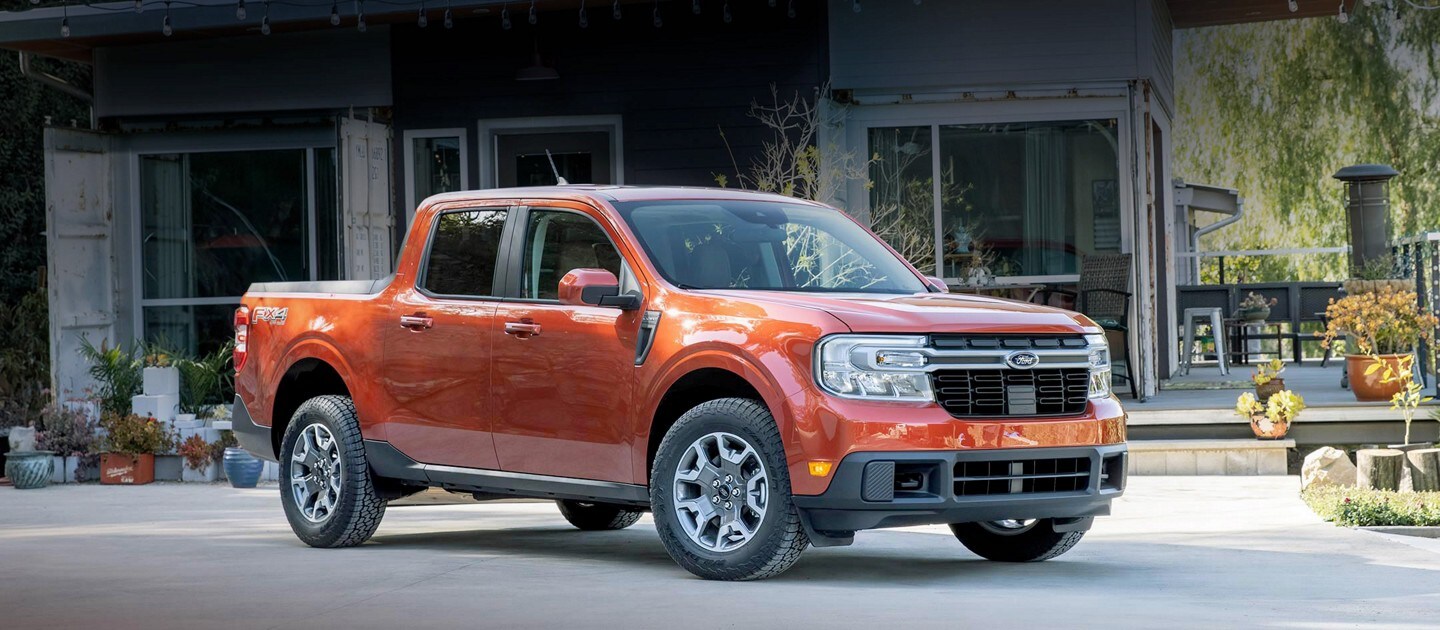 Le Ford Maverick LARIAT 2022 stationné devant une maison munie de grandes portes vitrées et de plusieurs pots de plantes.