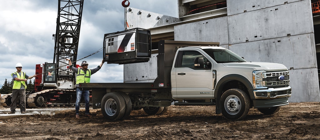 Un Ford Super Duty® à châssis-cabine 2026 stationné sur un chantier de construction alors qu’un objet est chargé sur la plateforme