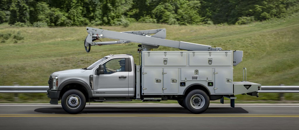 Un Ford Super Duty® à châssis-cabine 2026 avec une rallonge de flèche et un caisson utilitaire circulant sur une route