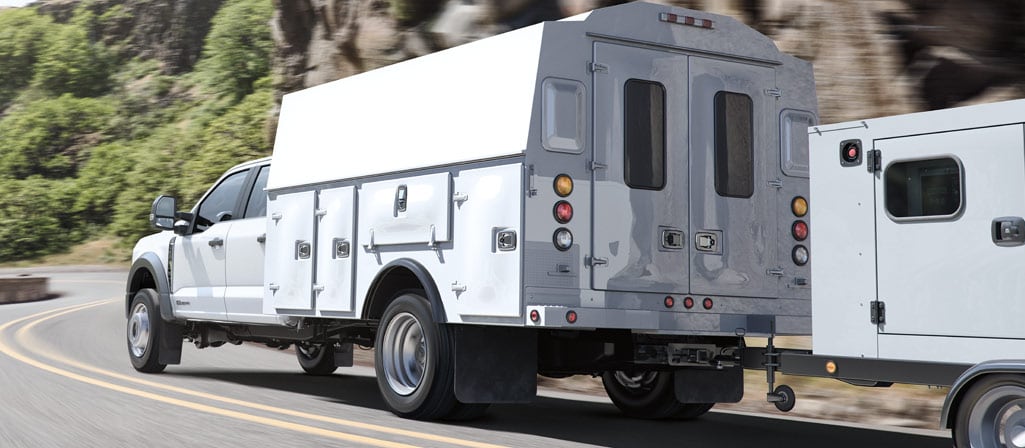 Un Ford Super Duty® châssis-cabine 2026 avec caisson utilitaire circulant sur une route à flanc de montagne