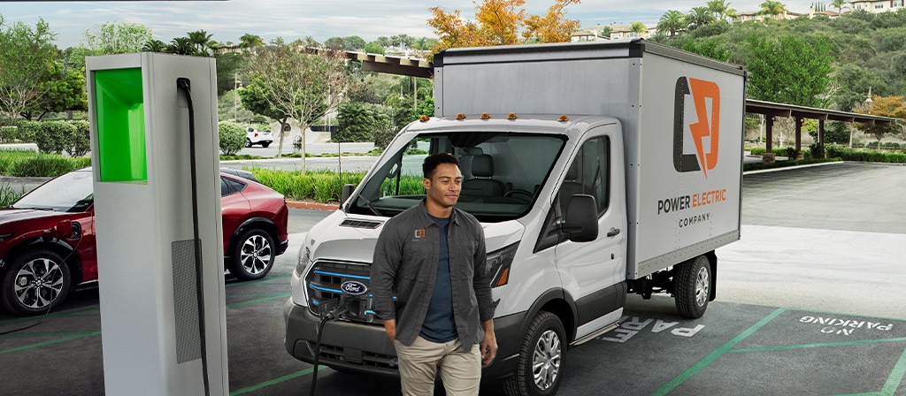 Une Ford E-Transit™ 2025 blanche stationnée en train de se recharger dans un terrain public