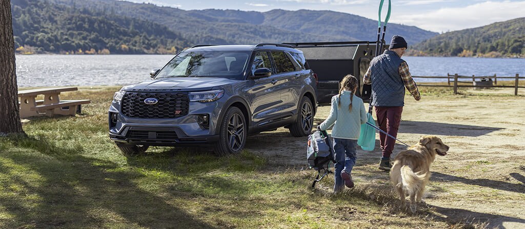 Ford Explorer® 2025 stationné près d’un lac avec une famille debout à l’extérieur du véhicule