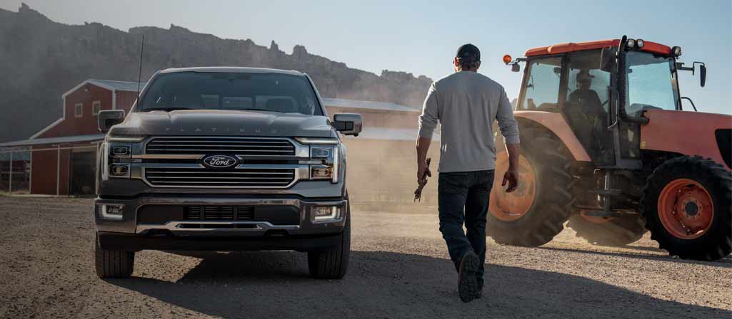 Une personne se dirigeant vers un camion F-150 Platinum® 2025 stationné dans une ferme