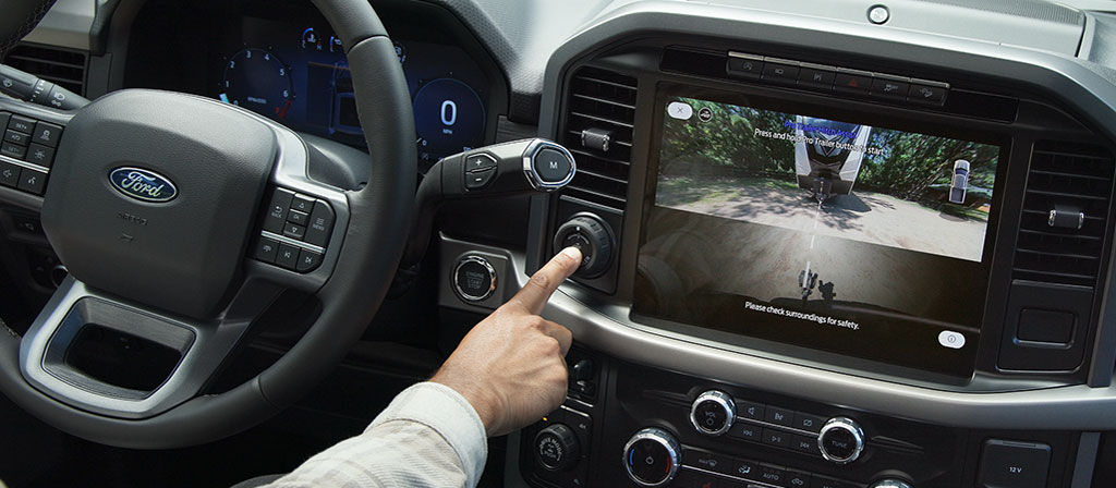 Une personne active le Pro Trailer Hitch Assist™ à l’aide du bouton Pro Trailer à l’intérieur d’un camion Ford F-150® 2025