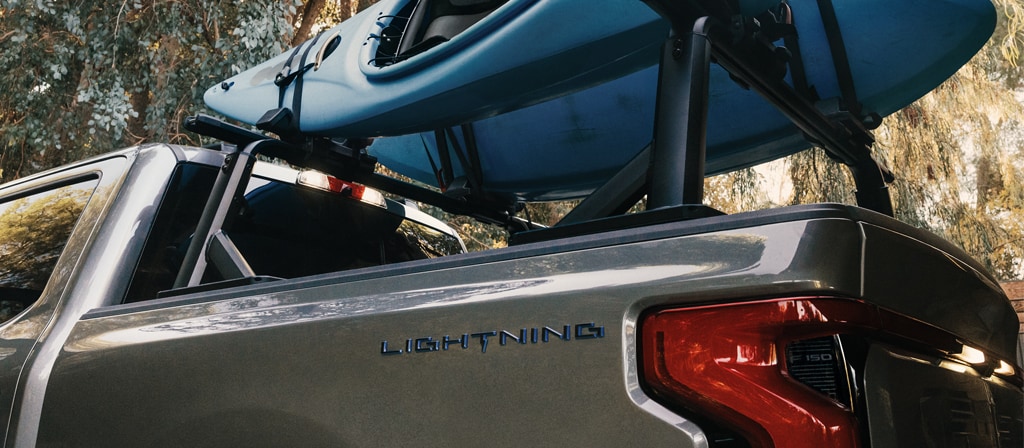 Un Ford F-150® Lightning® 2025 est stationné dans un endroit pittoresque avec des kayaks dans la caisse du camion