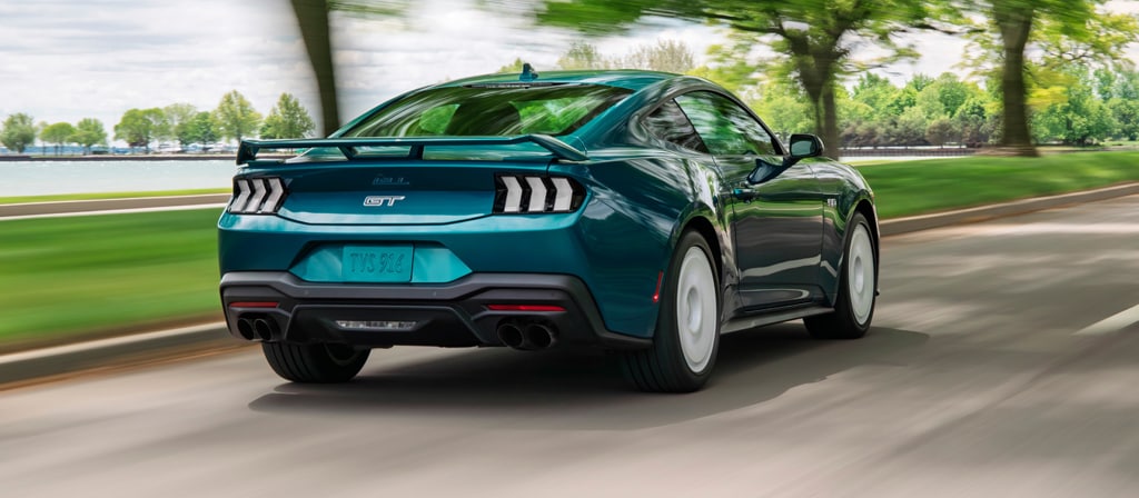 Vue arrière d’une Ford Mustang® GT Premium 2026 avec ensemble FX en option circulant près d’un lac