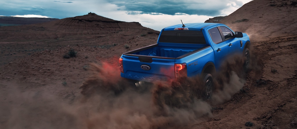 Vue arrière d'un camion Ford Ranger® 2025 étant conduit projetant de la poussière