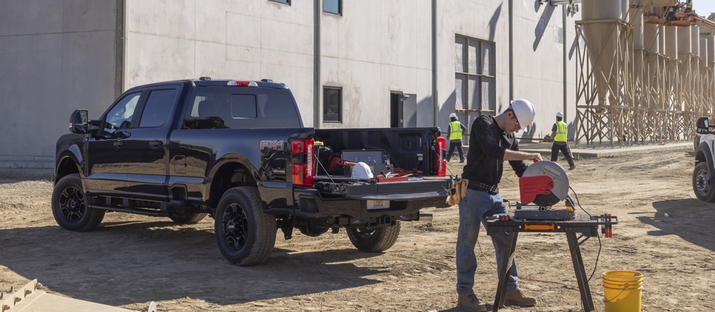 Camion Ford Super Duty® F-250® XL 2026 avec ensemble décor STX® stationné sur un chantier de construction avec une personne travaillant à proximité