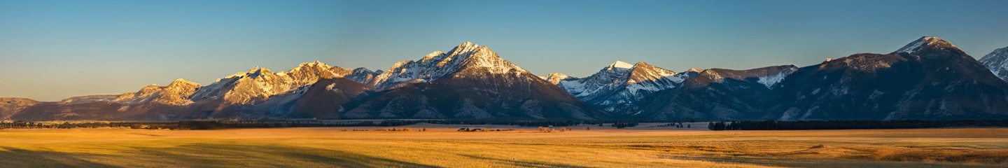 Une photo panoramique de coucher du soleil derrière une chaîne de montagnes