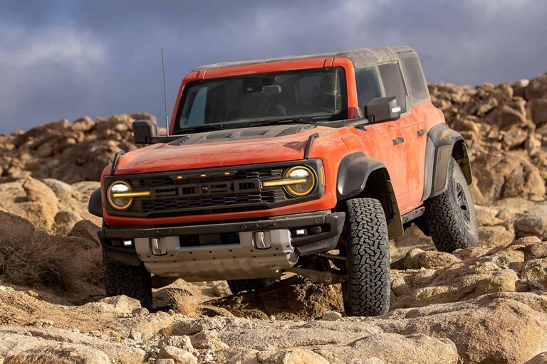 Ford Bronco® Raptor® 2023 quatre portes en rouge piment avec vernis teint métallisé circulant sur des rochers