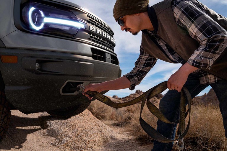 VUS Ford Bronco® Sport 2023 avec un homme accrochant une sangle aux crochets de remorquage avant