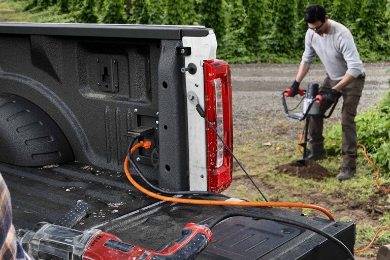 Un cordon d’alimentation va de la prise de courant dans la caisse à une tarière de terre électrique en fonction