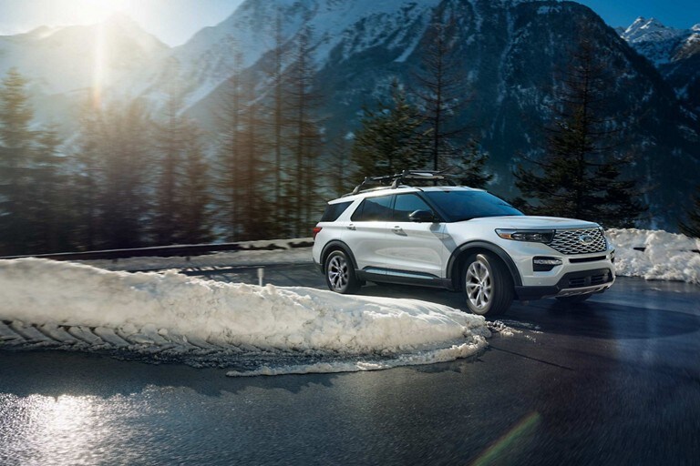 Le VUS Ford Explorer® 2023 conduit sur une route sinueuse entre des bancs de neige