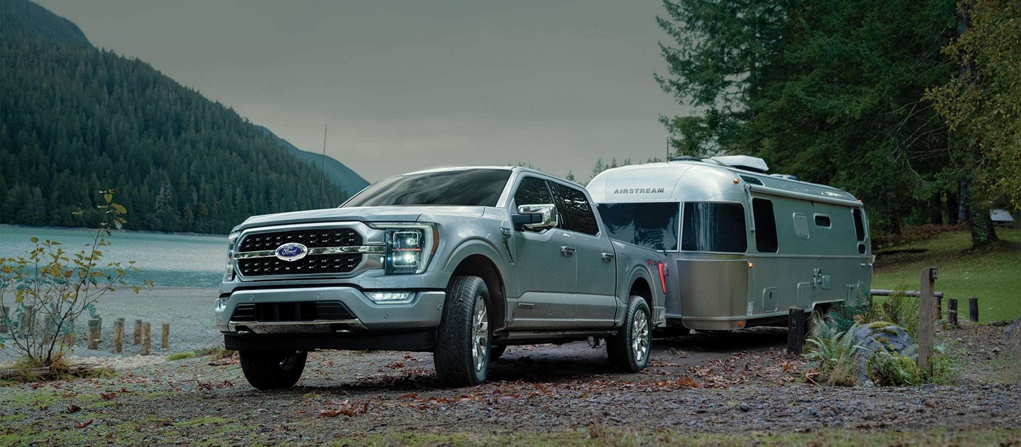 Un camion Ford F-150® 2023 fixé à une caravane sur un terrain de camping