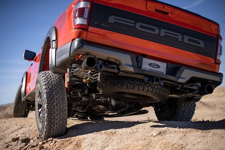 Gros plan sur la suspension arrière du camion Ford F-150® Raptor® 2023 lorsqu’il conduit sur un terrain accidenté