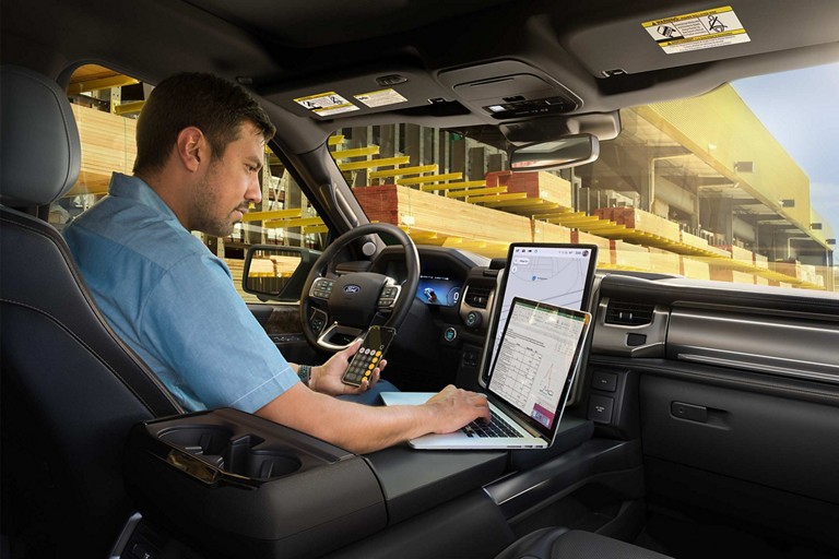 Intérieur d’un Ford F-150 Lightning® 2025 avec une personne utilisant un ordinateur sur la surface de travail intérieure