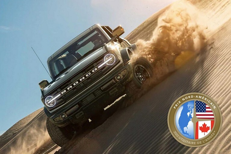 Ford Bronco® Wildtrak™ 4 portières 2022 en gris cactus conduit sur une dune de sable