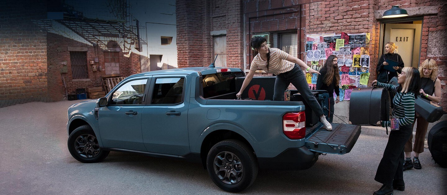 Un groupe de musiciens déchargeant leur équipement du plateau de leur Ford® Maverick 2022 couleur Zone 51