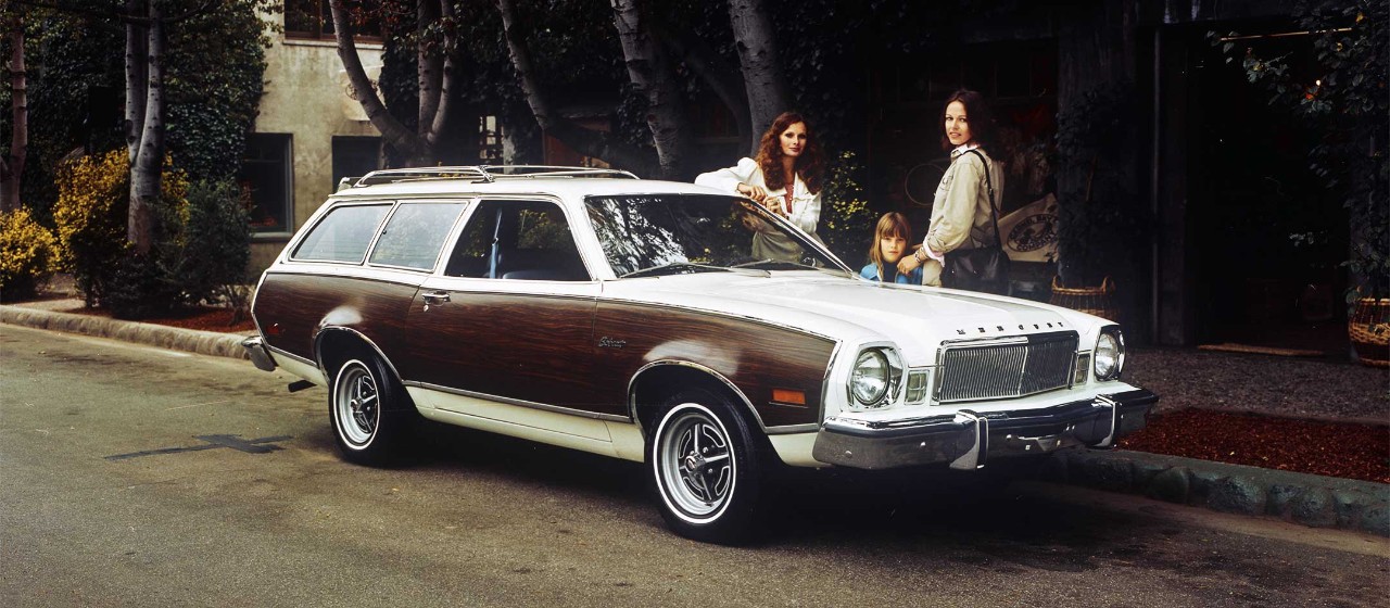 Deux femmes et un enfant debout près d'une familiale Mercury