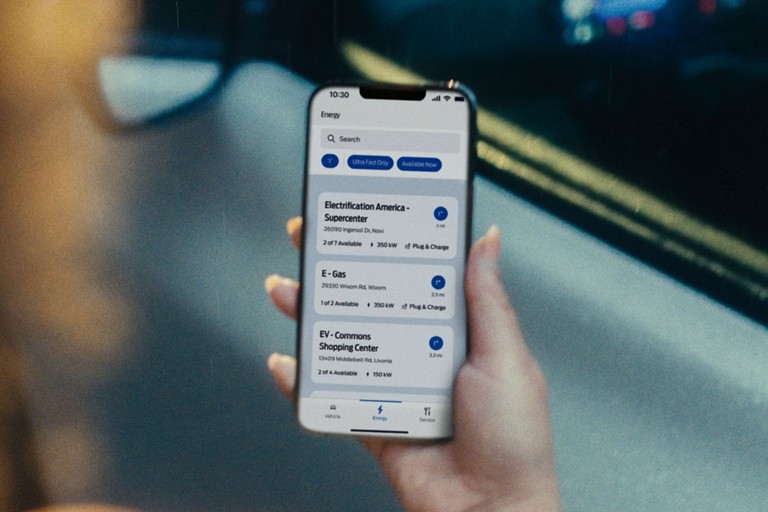 Une personne tient un téléphone intelligent affichant l’emplacement de stations de recharge publiques.